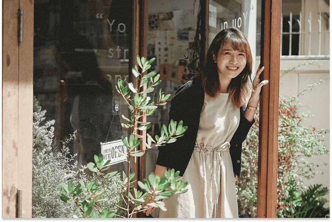 A happy client smiles outside a shopfront