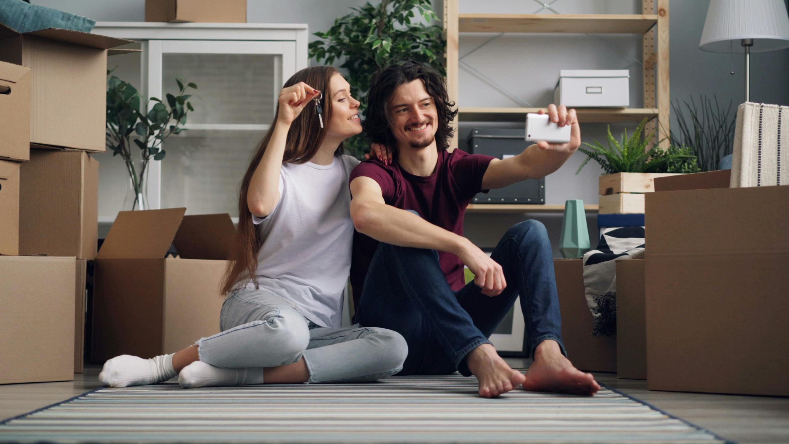 A couple take a selfie together in their new home, surrounded by moving boxes